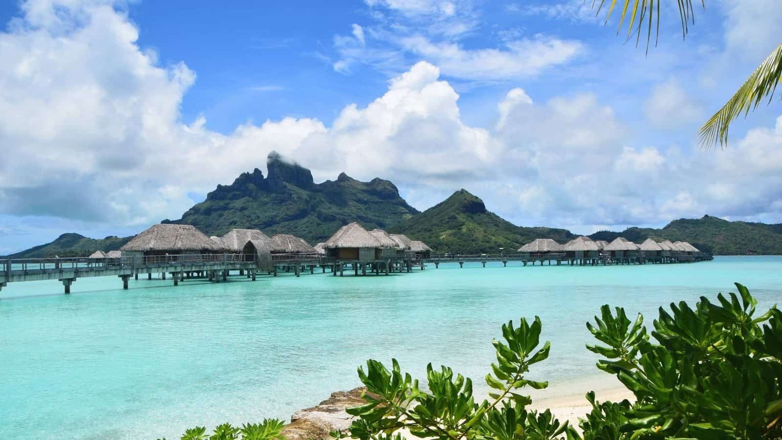 Overwater bungalows in Bora Bora with turquoise lagoon and mountain backdrop.