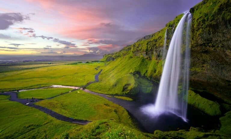 Seljalandsfoss waterfall pouring over green cliffs at sunset, Iceland