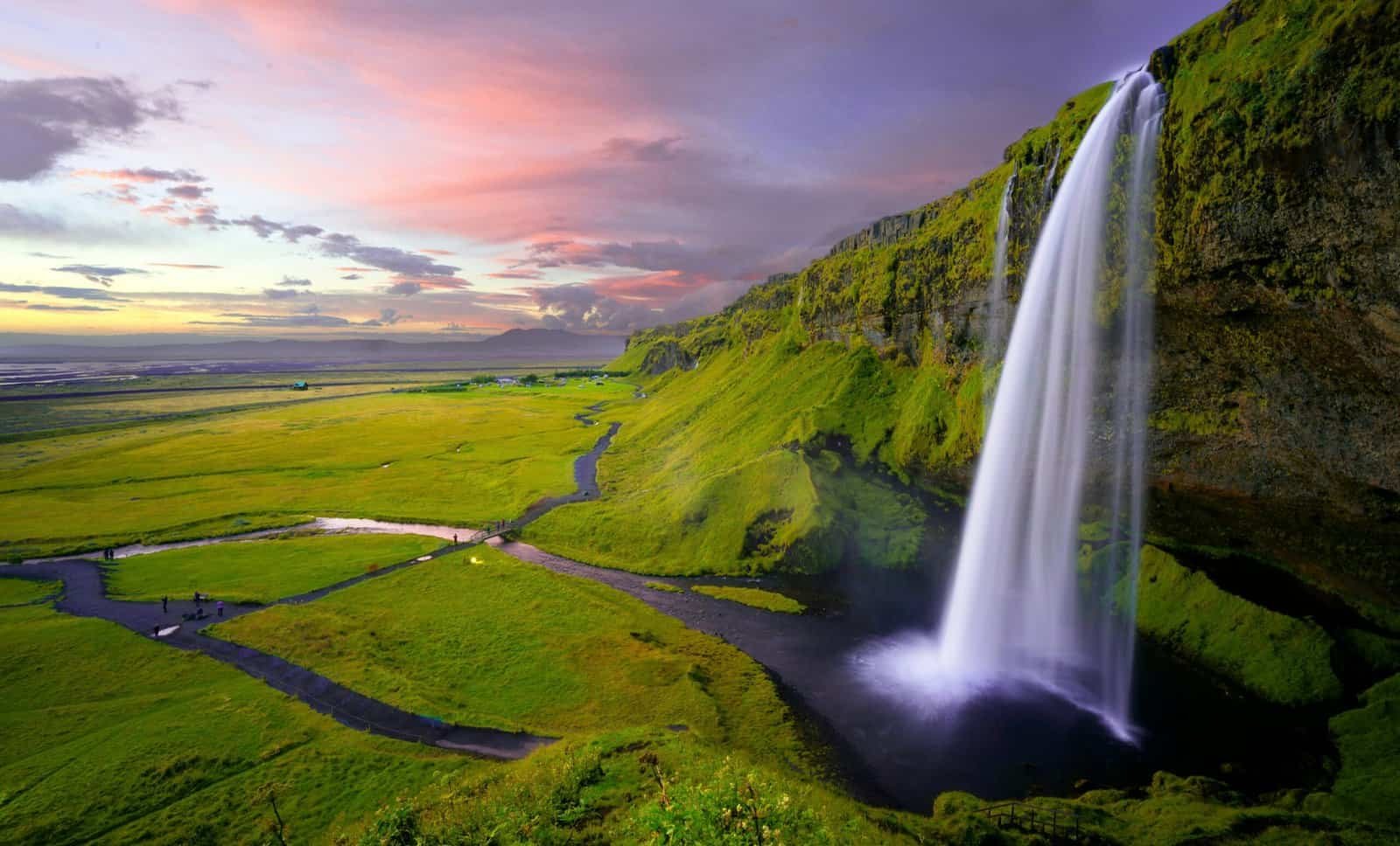 Seljalandsfoss waterfall pouring over green cliffs at sunset, Iceland