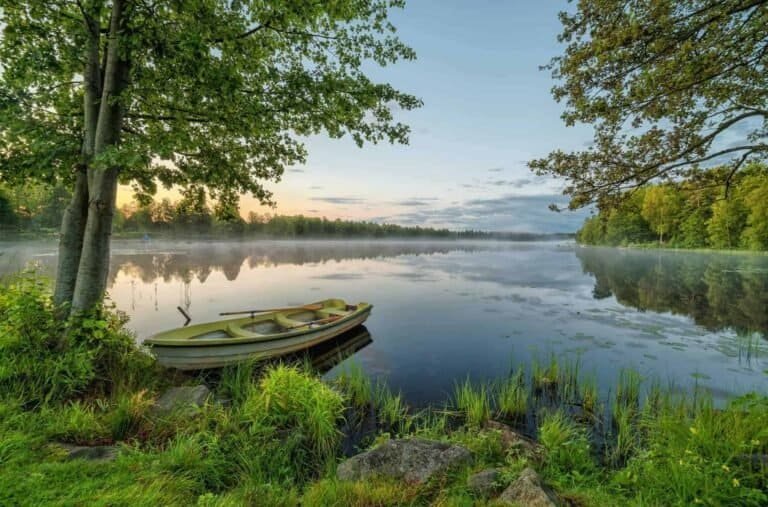 A rowboat moored at a quiet Nordic lake shore at dawn. Five Small Nordic Countries