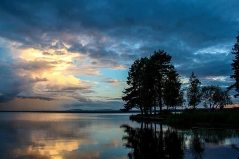 A wooded islet reflected in still water, Swedish archipelago at dusk