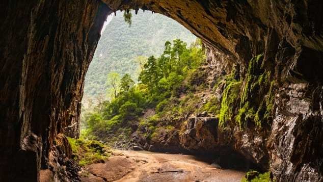 The vast mouth of Son Doong cave in Phong Nha-Ke Bang, with jungle beyond and people for scale